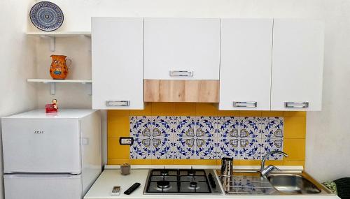 een kleine keuken met witte kasten en een spoelbak bij Il Limoneto di Lulù, holidays among the lemon trees in Minori