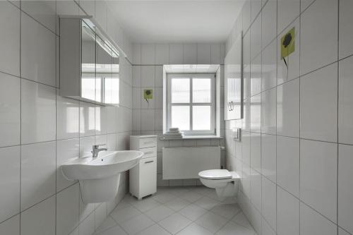 a white bathroom with a sink and a toilet at Apartamenty KAPRYS in Duszniki Zdrój