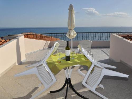 a table and chairs with a bottle of wine on a balcony at Giannis Maria Apartments in Psakoudia