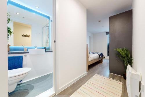 a bathroom with a toilet and a sink and a bed at Student Only Canvas Walthamstow in London in London
