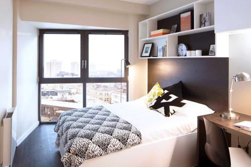 a bedroom with a bed and a desk and a window at Premium Studios and 2 Bed Apartments at Chapter Old Street in London in London