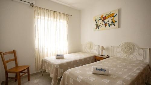 a bedroom with two beds and a chair and a window at Villa Monte Bixo - Free WIFI . Swimmning Pool - BY BEDZY in Assumadas