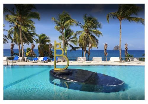 a resort swimming pool with a sign in the water at Studio Caliente vue panoramique Rocher du Diamant in Le Diamant