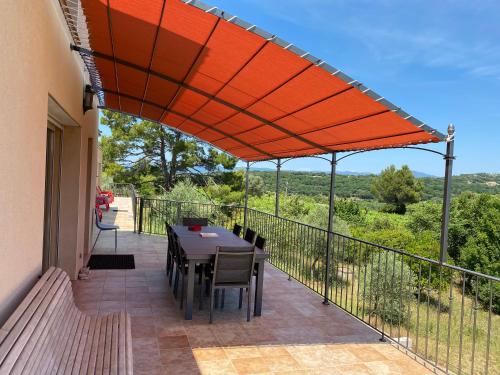 a patio with a table and chairs under an orange umbrella at DOMAINE MAXXIM in Clermont-lʼHérault