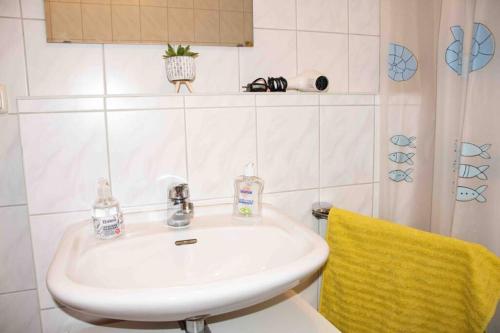 a bathroom with a white sink and a yellow towel at Gut und Günstig in Leipzig - zentrumsnah - inkl Fahrräder, Netflix und Tiefgaragenstellplatz in Leipzig