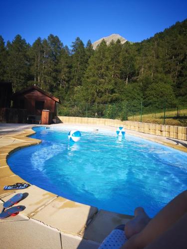 a pool of blue water with two people in it at Chalet calme in Saint-Léger-les-Mélèzes