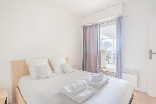 a bedroom with a white bed with towels on it at La Pause Bassin, charmant appartement dans le centre in Arcachon