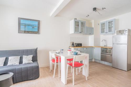 Il comprend un salon avec une table blanche et une cuisine. dans l'établissement La Pause Bassin, charmant appartement dans le centre, à Arcachon