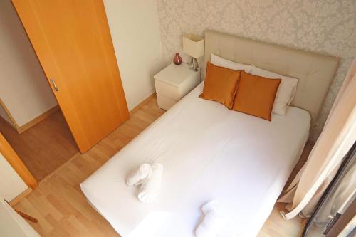 a small bedroom with a white bed with orange pillows at Bcn-rentals apartments in the Old town in Barcelona