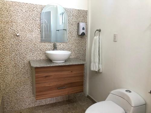 La salle de bains est pourvue d'un lavabo, de toilettes et d'un miroir. dans l'établissement Bungalow 19 Cozy room at just steps from the beach and in town center, à Sosúa