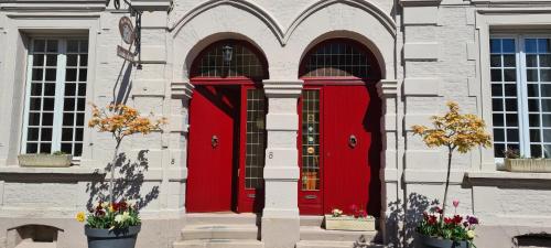 zwei rote Türen an der Seite eines Gebäudes in der Unterkunft Au Bois Dormant in Huby-Saint-Leu