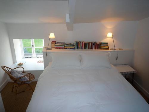 a bedroom with a white bed and a chair and a window at The Old Barn at Trymwood in Bristol