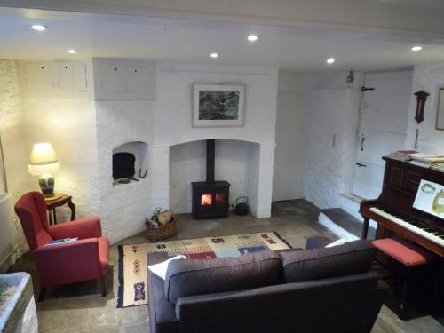 a living room with a fireplace and a couch and a piano at The Old Barn at Trymwood in Bristol