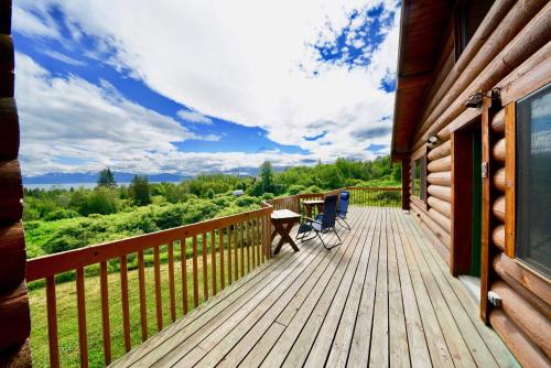 a wooden deck with chairs and a table on a house at Flat Fish Lodge B&B and Event Center in Homer