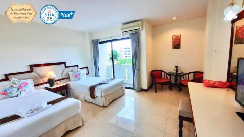 a hotel room with two beds and a television at Mei Zhou Phuket Hotel - SHA Plus in Phuket Town