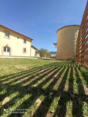 a building and a grassy field with a silo at Casale Viridi - nel fresco delle colline Umbre in Narni