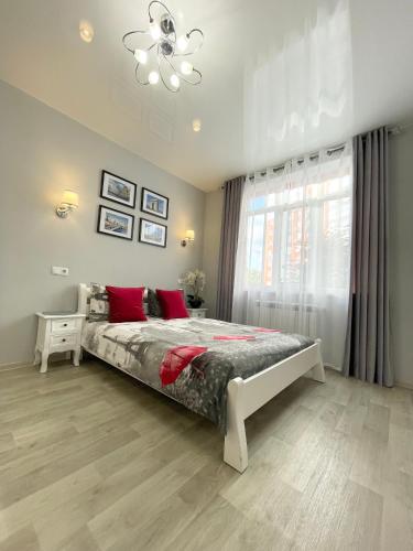 a bedroom with a bed with red pillows and a window at Apartment Studio PARIS 2 in Irpin
