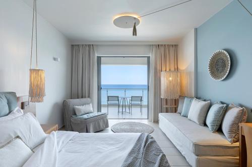 a living room with a couch and a living room with the ocean at Anastasia Hotel & Suites Mediterranean Comfort in Karistos