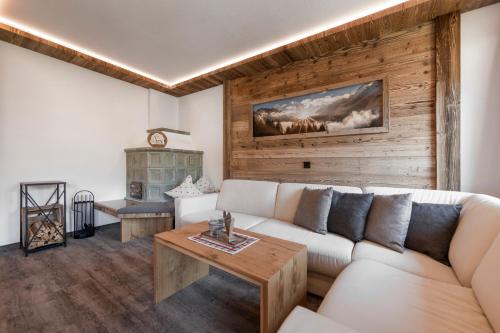 a living room with a white couch and a wooden wall at Alpenhof in Lermoos