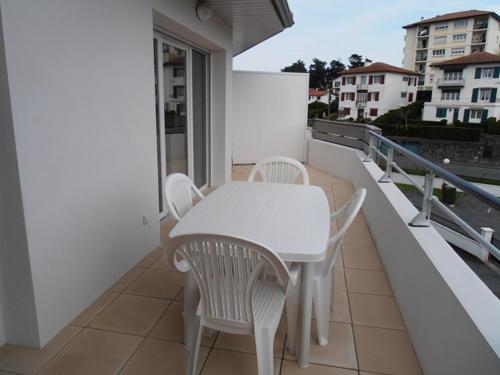 une table blanche et des chaises sur un balcon dans l'établissement Adartza - Bien moderne avec grand balcon et parking, à Saint-Jean-de-Luz