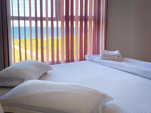 two beds in a room with a large window at Amphora Vibes in Vama Veche