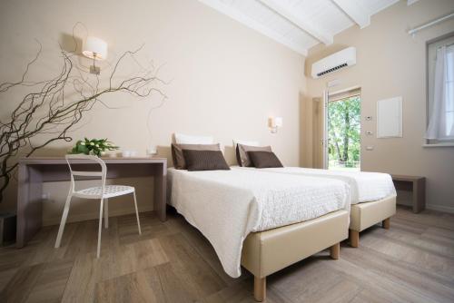 a white bedroom with a bed and a desk at Agriturismo La Galizia in Cuggiono
