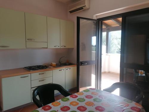 a kitchen with a table and chairs and a kitchen with white cabinets at La Piana Di Calena in Peschici