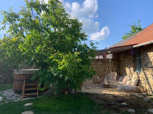 a tree in front of a house with a swing at Dejavu Ház in Szentantalfa