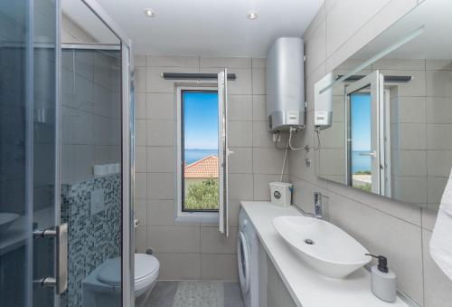 a bathroom with a sink and a toilet and a window at Villa Simon in Makarska