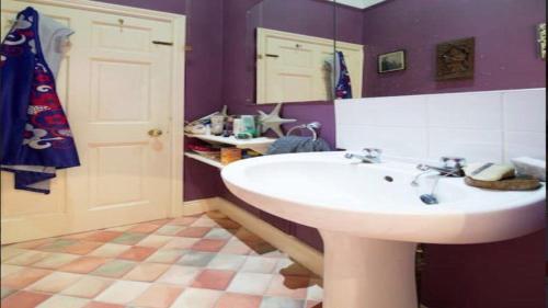 a bathroom with a white sink and purple walls at Lovely 3-Bed House in Cheltenham in Cheltenham