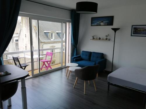 uma sala de estar com um sofá azul e uma varanda em Appartement proche mer et plage em Douarnenez