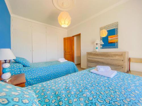 a bedroom with two beds with blue comforter at Apartamento em Burgau com vista deslumbrante para o mar in Burgau
