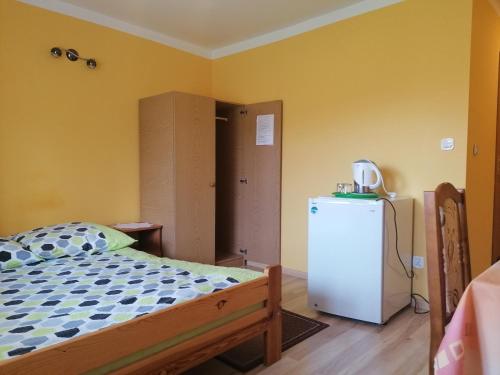 1 dormitorio con 1 cama y nevera. en Pokoje Pod Łukami en Solina