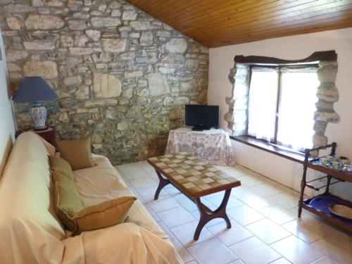 sala de estar con sofá y pared de piedra en Chibau Berria-Aperçu mer et montagne à côté de la plage en Saint-Jean-de-Luz