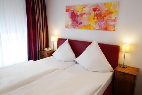 a bedroom with a white bed with two pillows at Hotel im Kupferkessel in Cologne