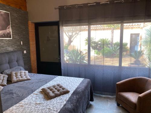 a bedroom with a bed and a chair and a window at HOTEL NATURE LE LOFT in Pierrelatte