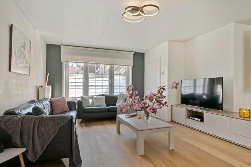 a living room with a couch and a tv at Huswell - Summer-house with sunny garden nearby beach in Knokke-Heist