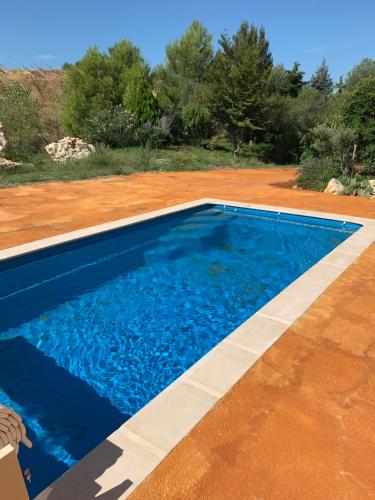 a swimming pool with blue water in a yard at HOTEL NATURE LE LOFT in Pierrelatte