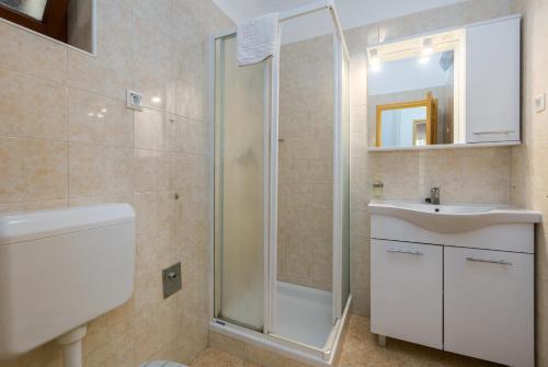 ein Badezimmer mit Dusche, Waschbecken und Spiegel in der Unterkunft Apartments Maria in Poreč