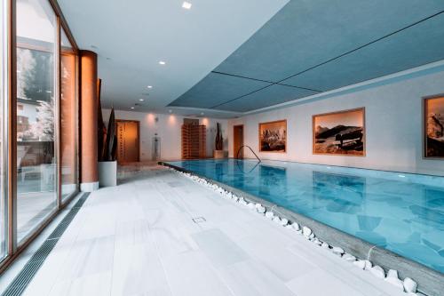 - une grande piscine dans un bâtiment avec une grande piscine dans l'établissement Boutique Hotel Nives - Luxury & Design in the Dolomites, à Selva di Val Gardena