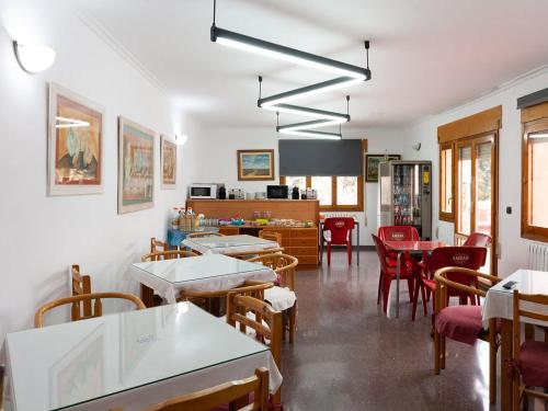 uma sala de jantar com mesas e cadeiras e uma cozinha em Hostal Gabás em Borja