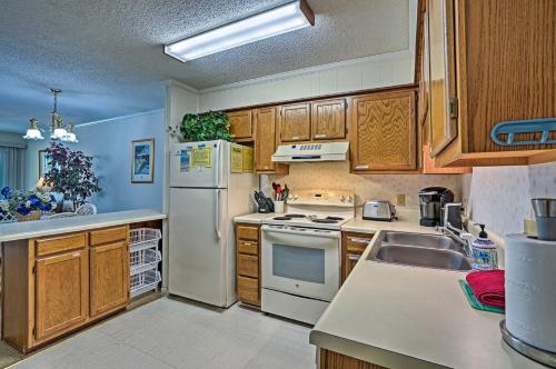 a kitchen with a white refrigerator and wooden cabinets at Coastal Condo with Pool Access - Walk To Beach! in Isle of Palms