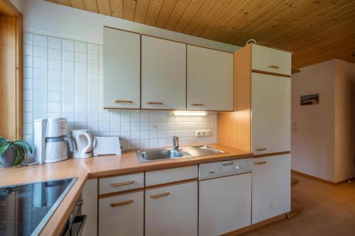 a kitchen with white cabinets and a sink at Ferienbauernhof Oberhauser in Schoppernau