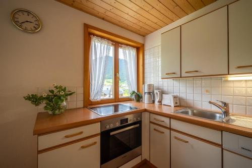 a kitchen with a sink and a clock on the wall at Ferienbauernhof Oberhauser in Schoppernau