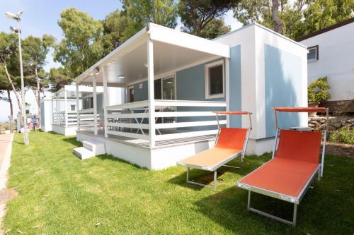 a tiny house with two chairs sitting on the grass at Porto Pirrone Camping in Leporano