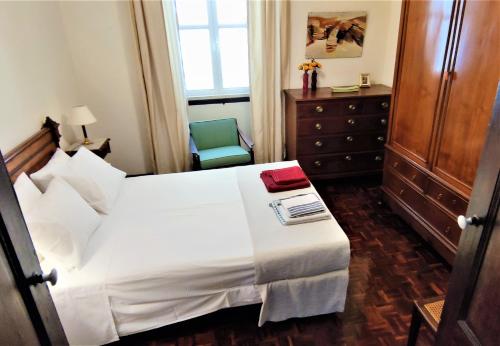 een slaapkamer met een wit bed en een stoel bij Quinta dos Reis in Alcantarilha
