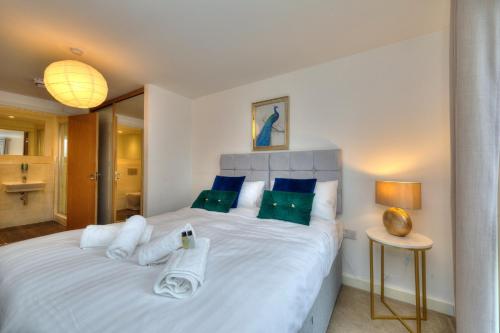 Executive Oakgrove Apartment by PAY AS U STAY في ميلتون كينز: غرفة نوم مع سرير أبيض كبير مع وسائد زرقاء