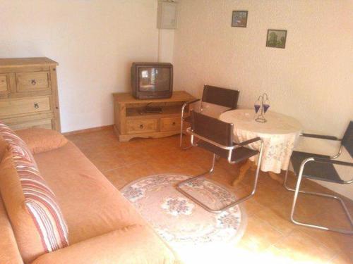 uma sala de estar com um sofá, uma mesa e uma televisão em kleines-Ferienhaus-nur-5-Auto-min-von-Binz em Lubkow