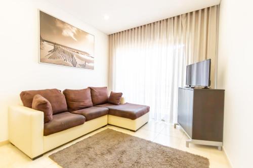 a living room with a couch and a television at Apartamento Mar & Sol in Póvoa de Varzim