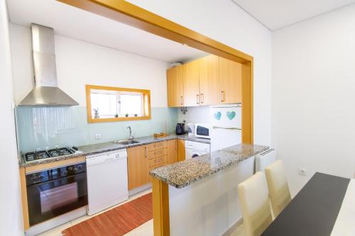 a kitchen with white appliances and wooden cabinets at Apartamento Mar & Sol in Póvoa de Varzim